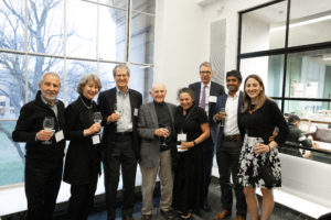 group of men and women in front of windows holding wine glasses