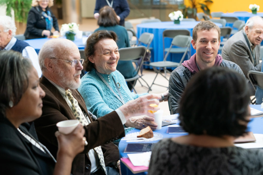 Several people chat at a table with coffee