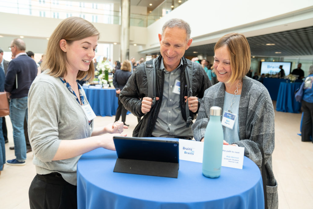 Female graduate student explains something on an iPad to man and woman