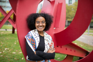 Amanuella Mengiste in front of a red metal sculpture