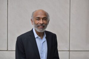 Professor Emery N. Brown stands in a black blazer and blue button down shirt