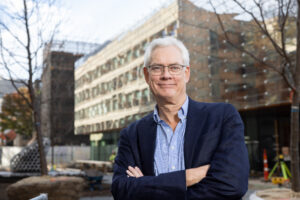 Rob van der Hilst crosses his arms and poses in front of a campus building