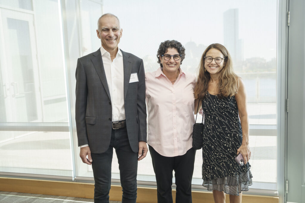 Professor Moungi Bawendi and his wife, Rachel Zimmerman, stand to either side of Dean Nergis Mavalvala in a joyous embrace