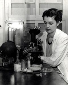 black and white photo of Margaret Hutchinson at a microscope